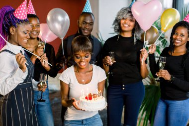 Grup Genç Afrika arkadaşıyla birlikte olan bir pasta mumlar ile onun elinde tutan bir çekici genç Afrikalı kadın Doğum günü kutluyor gülüyor