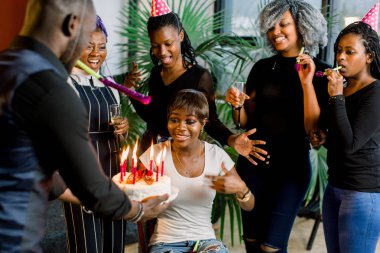 Doğum günü pastası parti de arkadaşlar çevrili mum üzerinde üfleme çekici Afro-Amerikan Kız portresi