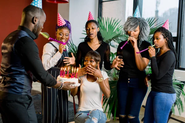 African Teenagers with party horns and a cake celebrating a birthday