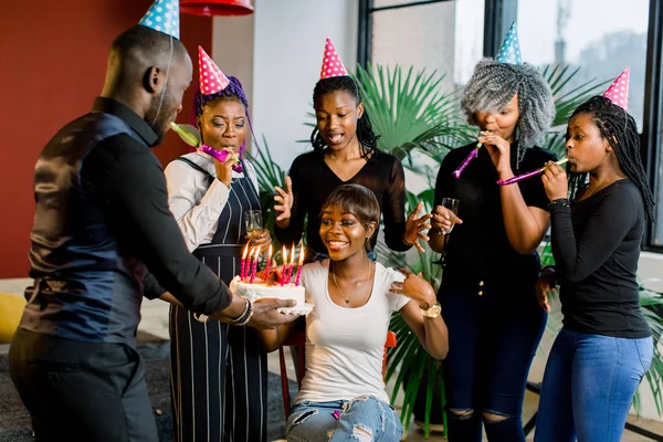 African Teenagers with party horns and a cake celebrating a birthday