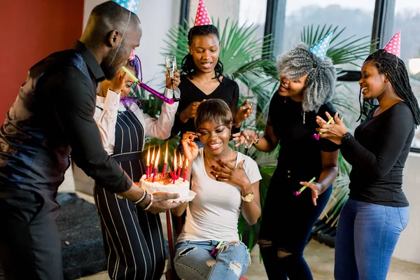 Friends presenting a birthday cake to the african girl