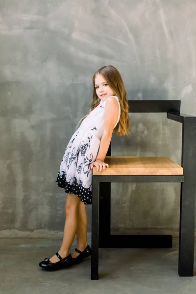 Kumral Beyaz Elbiseli Küçük Bir Güzel Kız Bir Sandalyeyle Standları — Stok fotoğraf