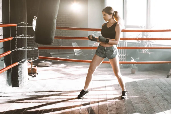 Uma pugilista a bater num saco enorme num estúdio de boxe. Mulher boxer formação duro . — Fotografia de Stock