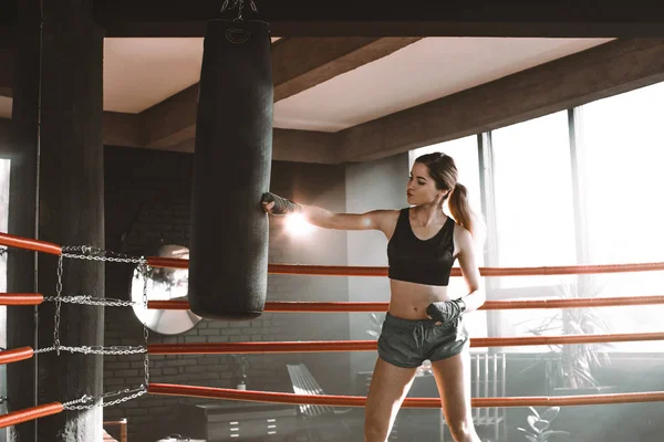 Uma pugilista a bater num saco enorme num estúdio de boxe. Mulher boxer formação duro . — Fotografia de Stock