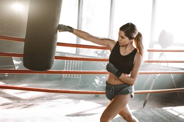 女拳击手在拳击演播室打了一个巨大的打击袋。女子拳击手刻苦训练. — 图库照片
