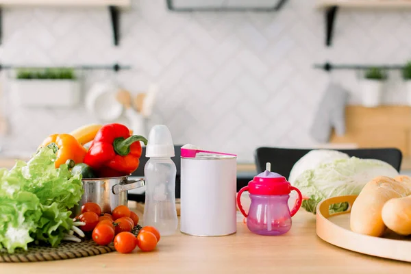 Υγιεινά τρόφιμα είναι στο τραπέζι στην κουζίνα. Φρέσκα λαχανικά και φρούτα, παιδικές τροφές, ψωμί και γάλα στο ξύλινο τραπέζι, σύγχρονη κουζίνα θολή φόντο — Φωτογραφία Αρχείου