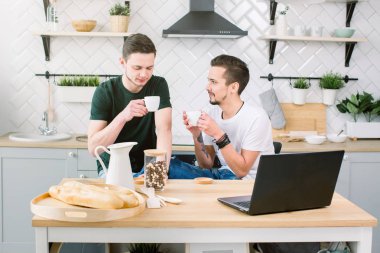 Eşcinsel çift mutfak görüntüsünü. Kahve içme ve dizüstü bilgisayar evde mutfak, Eşcinsel hayat kavramı çalışma çekici beyaz erkek