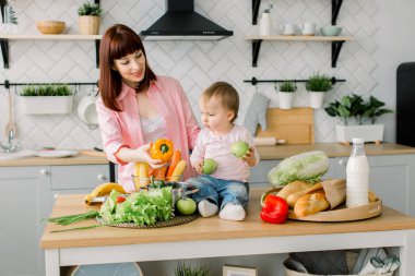 Sağlıklı beslenme. Mutlu aile anne ve bebek kız mutfakta sebze salatası hazırlar