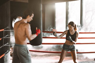 Bir kız nasıl yumruk vurmak için öğretim eğitmeni. Kız giyiyor boks bandaj ve baş koçu bir boks halka içinde eğitimle koru.