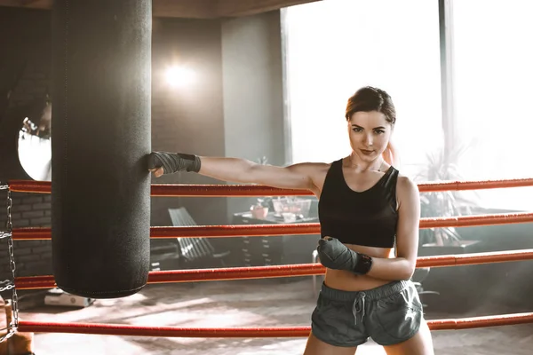 Mulher bonita e confiante boxeador atlético saco de perfuração durante a preparação de treinamento para a batalha . — Fotografia de Stock