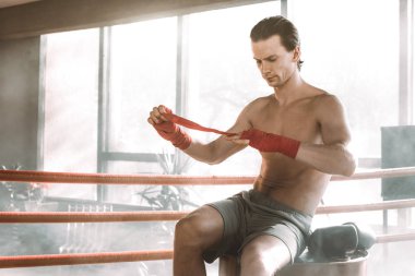 Genç yakışıklı boksör kavga veya eğitim boks ringde Kırmızı varil üzerinde oturan önce bandaj çeker. Bandaj için eğitim hazırlanıyor boks Fighter
