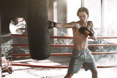 Erkek beyaz boksör boks studio parlak ışık ile boks torbasına yumruk. Spor, fitness, sağlıklı vücut, boks konsepti