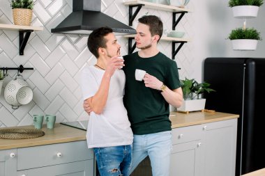Kahve, ev mutfak, closeup ile mutlu gay çift. Kahve içme ve diğer her mutfakta seyir yakışıklı homoseksüel erkekler