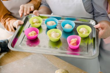 Muffins pişirme için hazırlanıyor. Hamur silikon renkli bardak tepsi pişirme metal yalan bölünmüş. Tepsi pişirme kek holding kadınlar eller Close-Up.