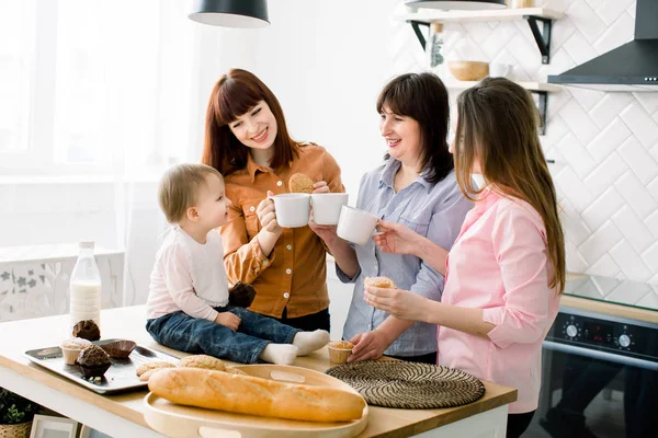 Atraktivní mladé ženy středního věku, Žena a malá roztomilá dcera se vaření v kuchyni. Milující rodina jíst jejich vdolky v kuchyni a pití kávy — Stock fotografie