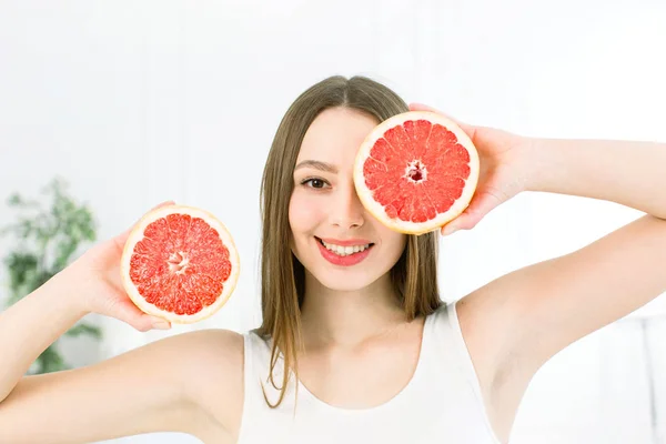 Egészséges, gyönyörű mosoly, aranyos boldog lány gazdaság grapefruit arca közel felét. Egészséges ételek fogalmát. Bőrápolási és kozmetikai. Vitaminok és ásványi anyagok. — Stock Fotó