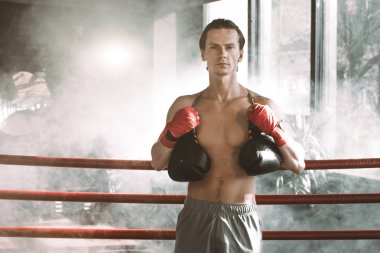 Ciddi genç kas boksör boks ringde adam. Boks eldivenleri üzerinde koyu arka plan kapalı omzuna asılmış.