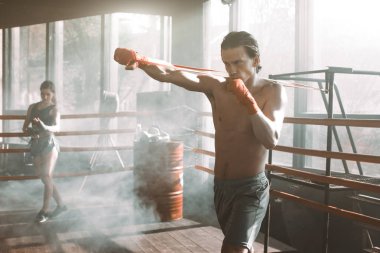 Yakışıklı adam spor salonunda boks ringde direniş band ile çalışma dışarı... Mükemmel şekilli kol ve sırt kasları.
