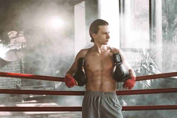 男子拳击手, 有肌肉发达的身体站在拳击场内。拳击手把胳膊放在拳击场的绳子上. — 图库照片