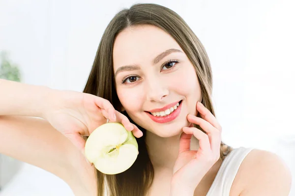 Hermosa sonrisa, dientes blancos y fuertes. Cabeza y hombros de mujer joven con sonrisa blanca como la nieve sosteniendo manzana verde, cuidado de los dientes . —  Fotos de Stock