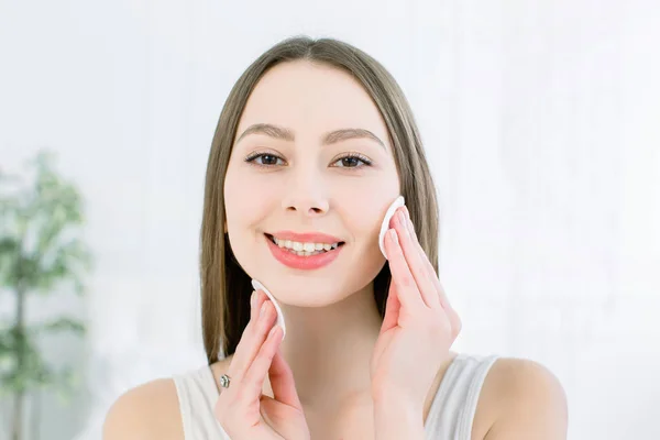 Bela Face de Jovem Mulher com Pele Fresca Limpa segurando almofadas de algodão de perto isoladas em branco. Retrato de Beleza. Mulher de Spa bonita sorrindo. Pele fresca perfeita. Conceito de cuidados com a pele e juventude — Fotografia de Stock