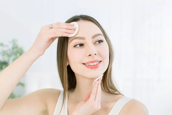 Cuidado de la cara. Piel fresca perfecta. Hermosa cara de mujer joven quitando el maquillaje. Mano de mujer con algodón. Piel limpia con algodón. Concepto de belleza, cuidado de la piel y problemas de la piel —  Fotos de Stock