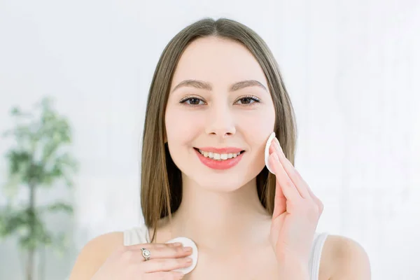 Bela Face de Jovem Mulher com Pele Fresca Limpa segurando almofadas de algodão de perto isoladas em branco. Retrato de Beleza. Mulher de Spa bonita sorrindo. Pele fresca perfeita. Conceito de cuidados com a pele e juventude — Fotografia de Stock