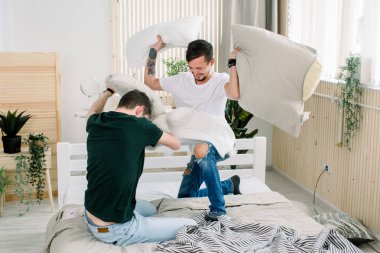Genç gay çift yastık sahip yatak odasında mücadele portresi
