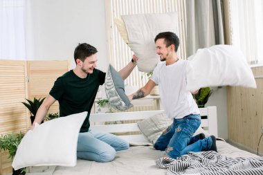 Genç gay çift yastık sahip yatak odasında mücadele portresi