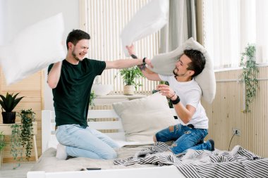 Mutlu genç gay çift yatakta eğleniyor. Birbirlerinin şirket zevk. Yastık savaşı