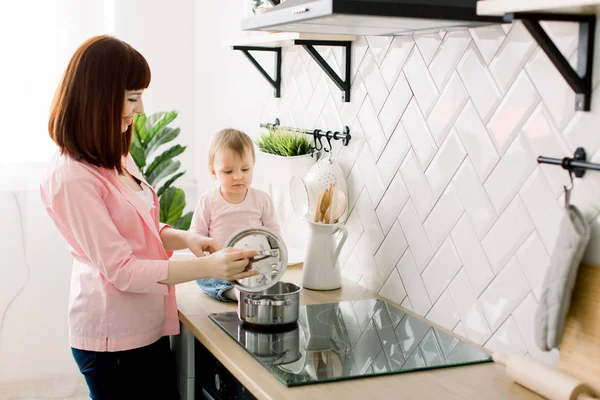 preparation of a family breakfast. mother and child daughter cook porridge in morning