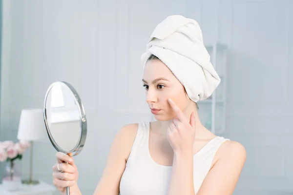 Potret wanita Kaukasia yang menarik tersenyum di studio putih bersih-bersih wajahnya melihat cermin menerapkan Foundation On Facial Skin — Stok Foto
