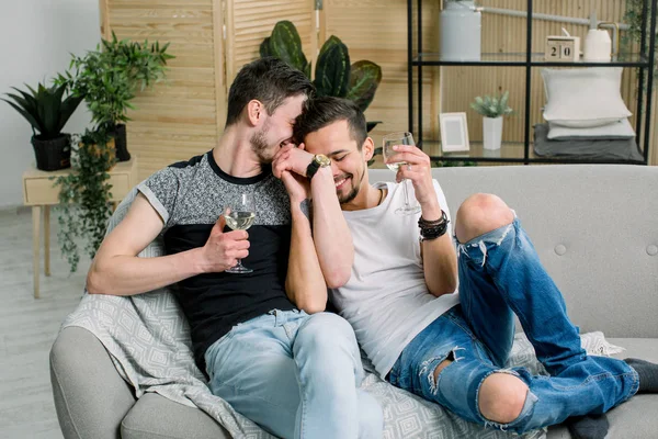 Gay couple drinking tea and chatting together on couch Stock Photo