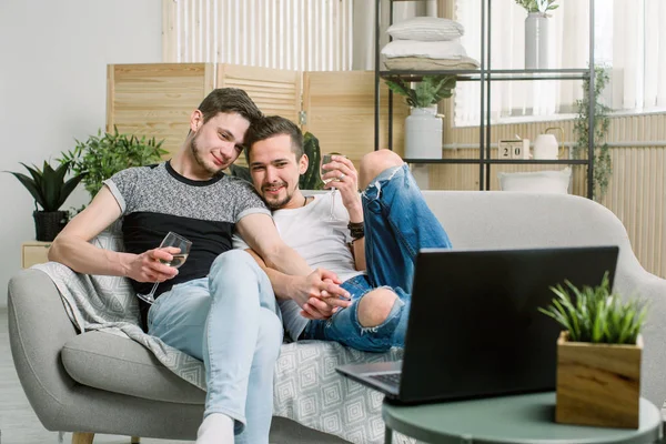 젊은 게이 부부는 인터넷을 서핑 하는 노트북 컴퓨터와 함께 큰 편안한 소파에 와인과 함께 편안한, 위에서 보기 — 스톡 사진
