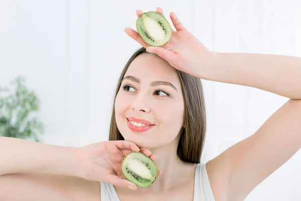 Belleza mujer sonriente y rebanadas de fruta kiwi - La mujer está haciendo dieta saludable aislado en el fondo claro, hembra caucásica — Foto de Stock