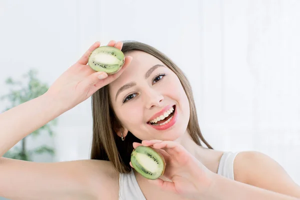 Belleza mujer sonriente y rebanadas de fruta kiwi - La mujer está haciendo dieta saludable aislado en el fondo claro, hembra caucásica — Foto de Stock