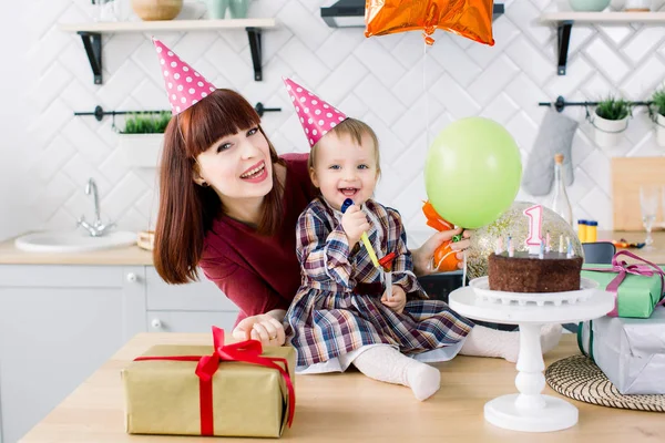 young beautiful mother and her little daughter are celebrating a birthday. cake with candles. happy birthday baby