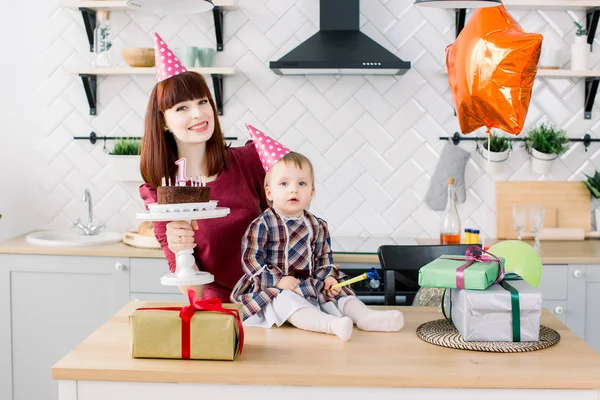 Fiatal gyönyörű anya és vele a kis lányom ünnepli a születésnapját. torta gyertyákkal. Boldog születésnapot baby — Stock Fotó