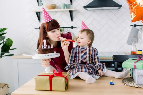young beautiful mother and her little daughter are celebrating a birthday. cake with candles. happy birthday baby