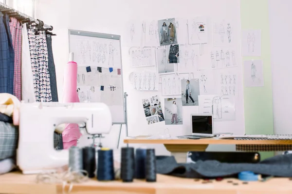 Креативный стол дизайнера моды или рабочее место с швейным оборудованием, тканями, шаблонами, современный стилист вдохновляющий офис, портниха ателье с одеждой на вешалках, кутюрье шоурум — стоковое фото