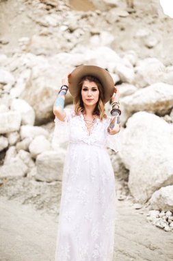 Açık kahverengi şapka ve beyaz rustik elbise güzel bir genç kadın gelin kum Kanyon arka planda duruyor. Elinde dövmeler ile şık genç kız