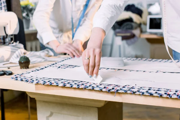 Крупным планом фотография женских рук портнихи, работающей с узорами шитья. Портной за работой, чертежная линия на ткани с мелом — стоковое фото