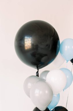 Beyaz arka plan üzerinde siyah, gri, mavi ve beyaz balonlar. Kutlama konsepti. Tatil için hava balonları, doğum günü partisi. Posterler veya kartpostallar için fotoğraf.