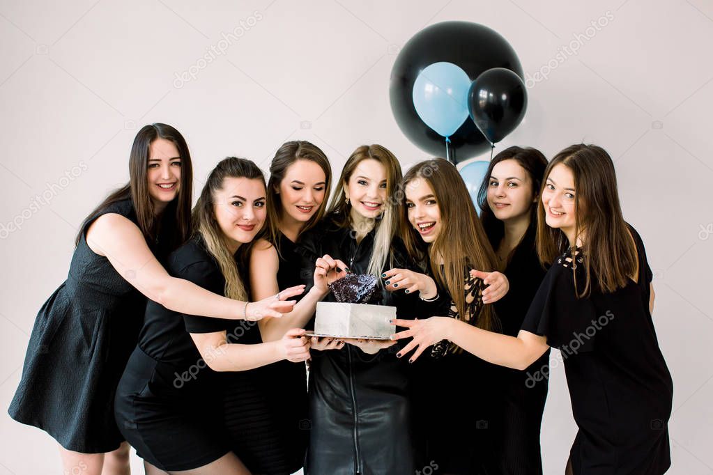 Jóvenes damas felices en vestidos negros celebrando su cumpleaños