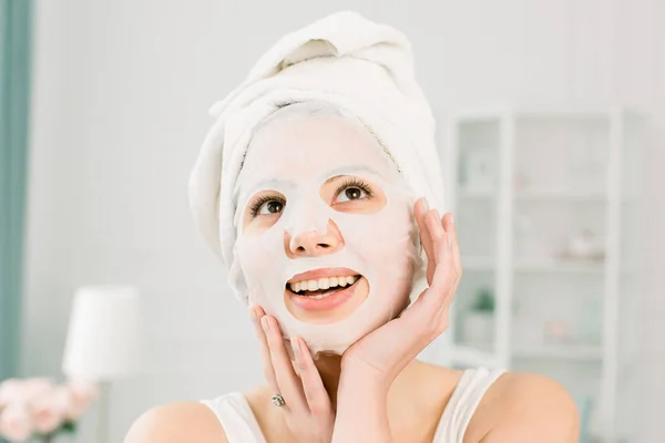 Wanita cantik dengan handuk putih di kepala, menerapkan masker wajah, konsep perawatan kulit. Spa, layanan kesehatan. Wanita dengan topeng pemurnian di wajahnya — Stok Foto