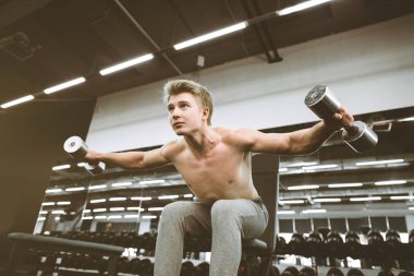 Halterile spor salonunda egzersiz sırasında konsantre sportif adam. Ağır ağırlıkları kaldırır, pazıları eğitir. Güzel göğüs kasları