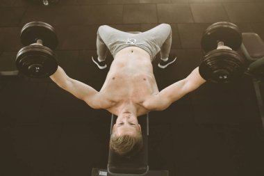 Spor kulübündeki dambıllı adam. Spor salonunda halter kaldıran mutlu vücut geliştirmeci. Fitness, spor, egzersiz ve sağlıklı yaşam tarzı kavramı