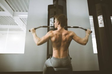 Yakışıklı güç atletik adam eğitim arka kasları kadar pompalama spor salonunda çekin. Spor salonunda güçlü vücut geliştirmeci trenler, sırtını trenler.