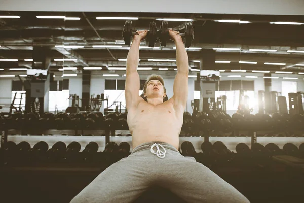 英俊的年轻皮菲健身男子在健身房锻炼哑铃。男子健美运动员在健身房锻炼举行哑铃 — 图库照片