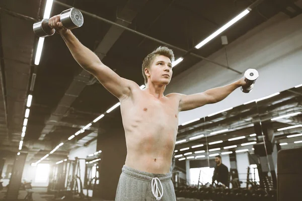 运动男子在健身房用哑铃锻炼的肖像。运动员男子锻炼与训练哑铃在健身房的二头肌肌肉 — 图库照片